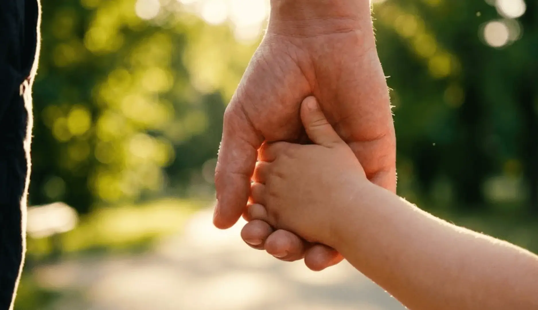 Gros plan main adulte tenant main enfant, symbole de guidance parentale bienveillante et de confiance